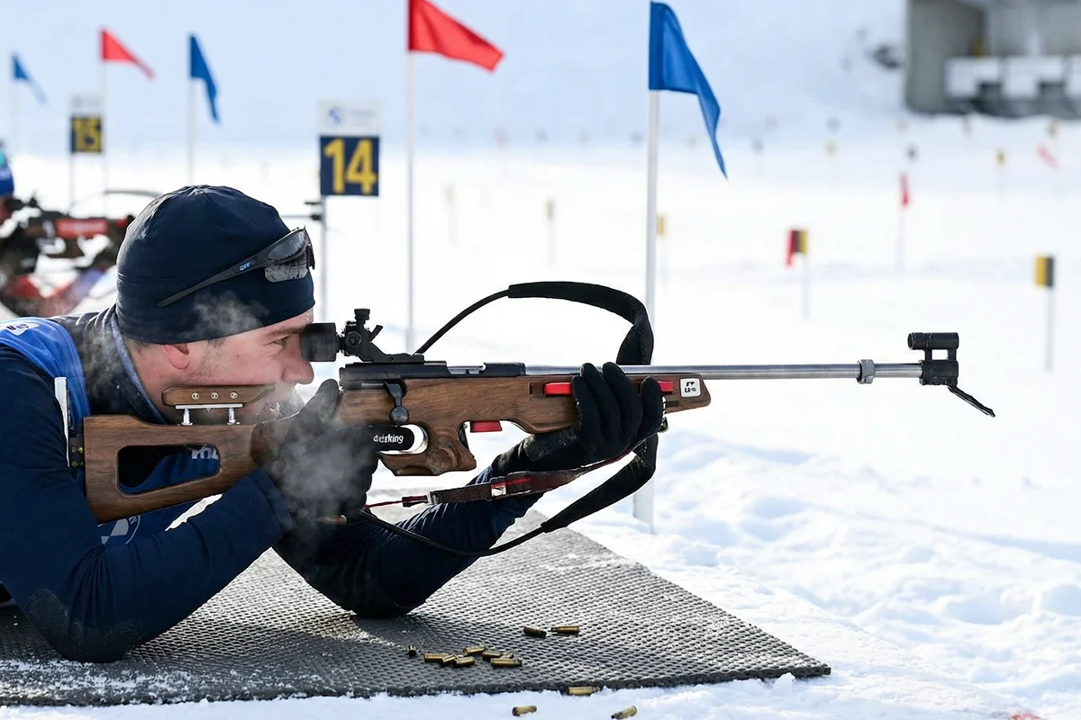 Biathlète en position de tir couché visant les cinq cibles à 50 mètres sur le pas de tir