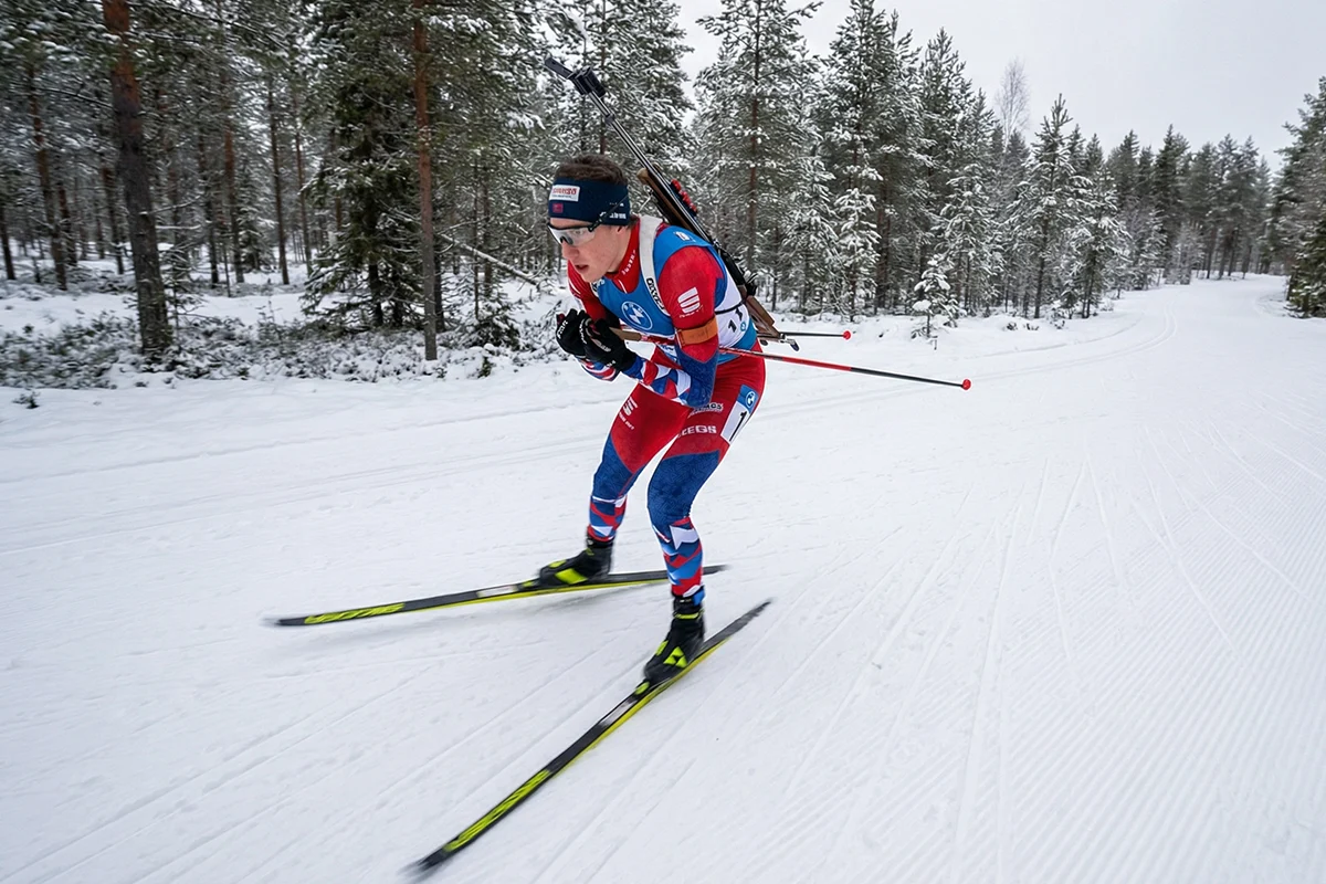 Biathlète en ski de fond approchant le pas de tir avec sa carabine pendant une course de biathlon